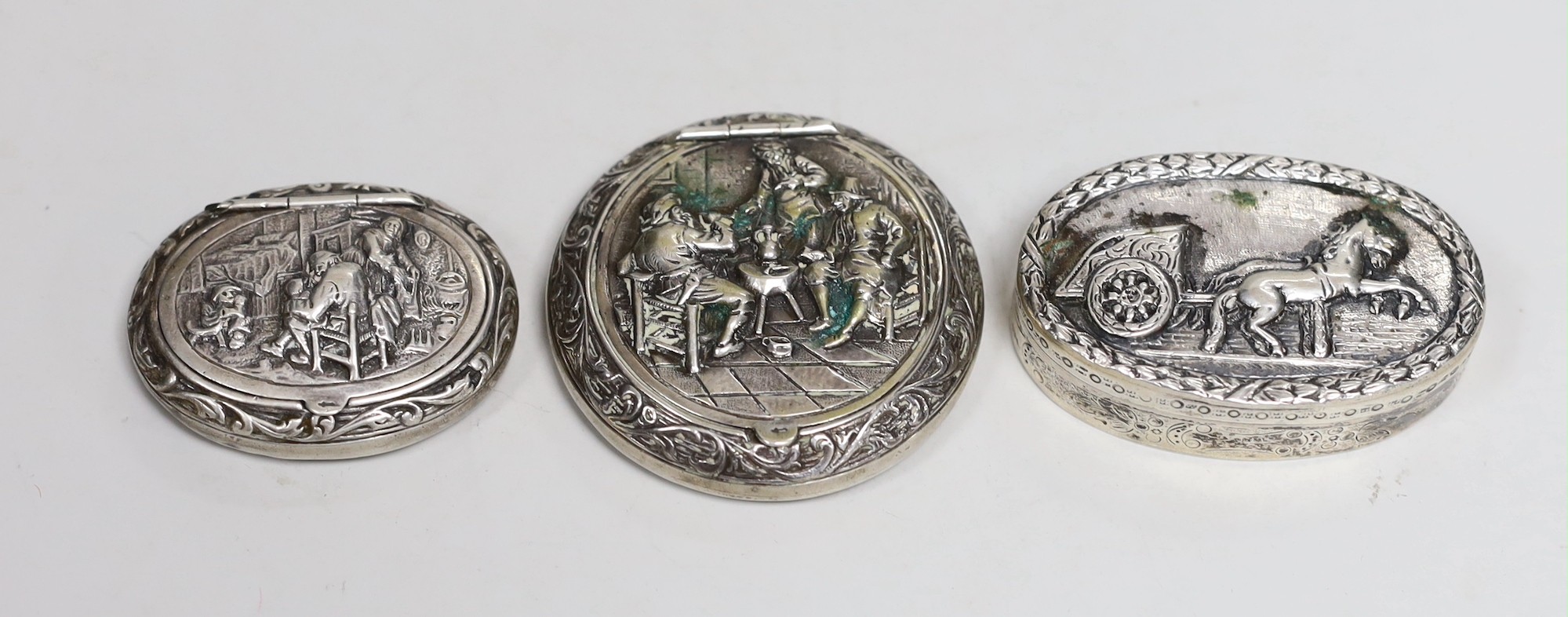 Two 19th century Dutch white metal snuff boxes, circular 56mm and oval and an 800 standard oval snuff box, decorated with horse and cart.